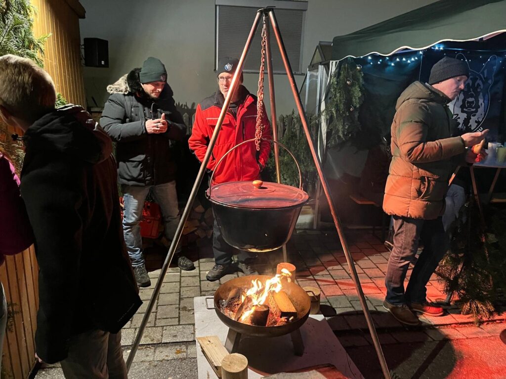Helferinnen und Helfer bei der Vorbereitung an einem Kessel über dem Feuer