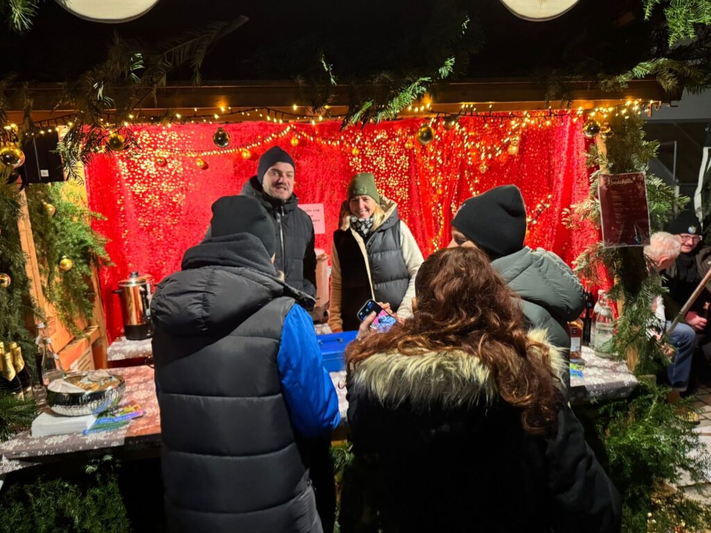 Gäste und Helfer im Gespräch am Weihnachtsmarktstand der Ortsgruppe